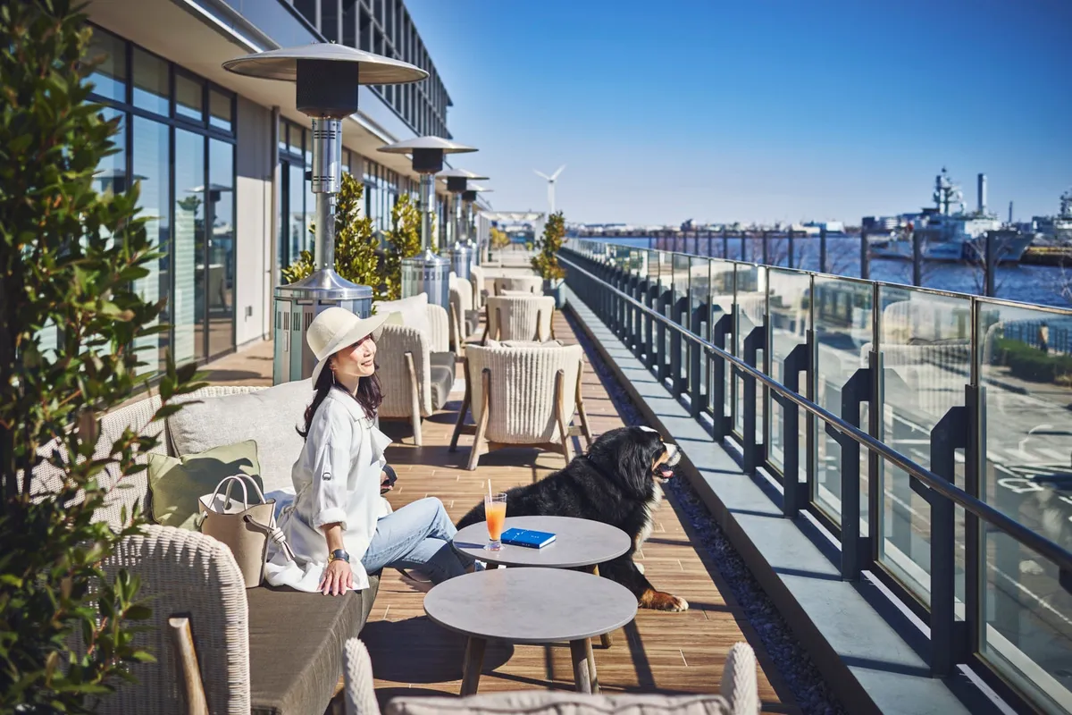 海を望む開放的なテラス席で愛犬と一緒にリラックスした時間を過ごす様子
