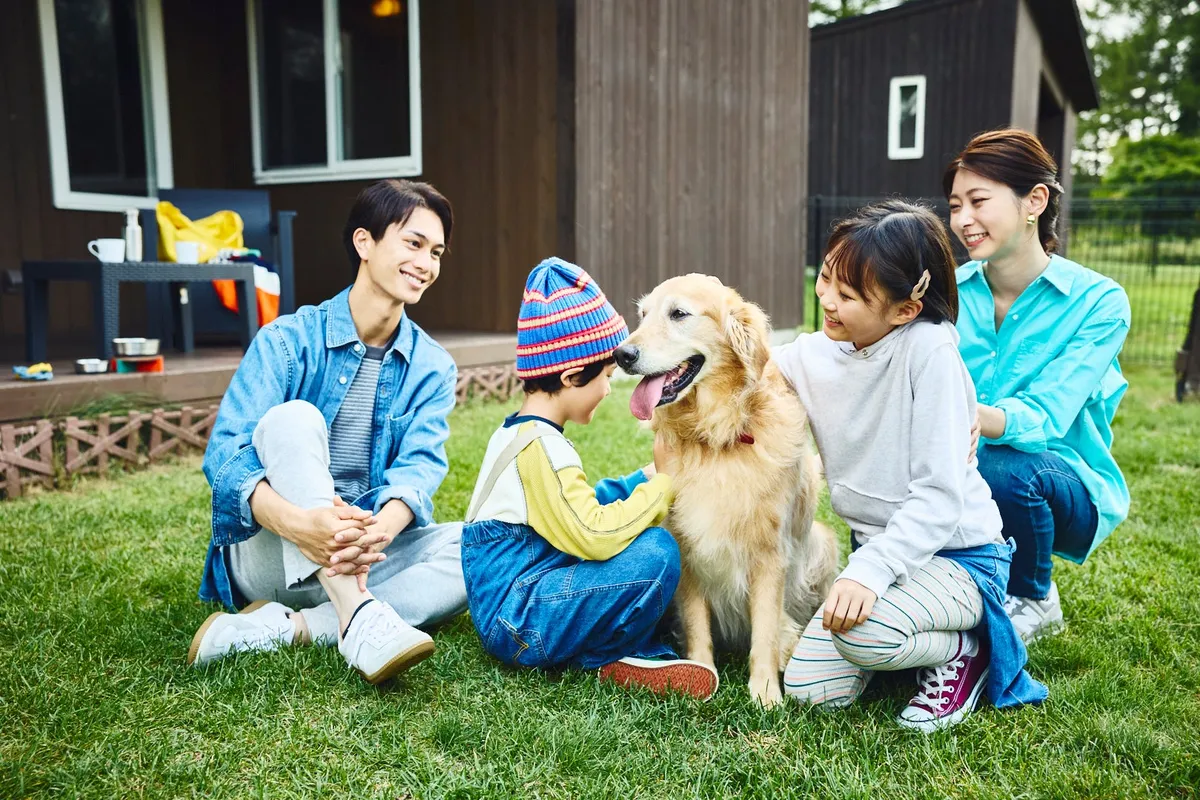 愛犬と芝生でくつろぐ家族の様子
