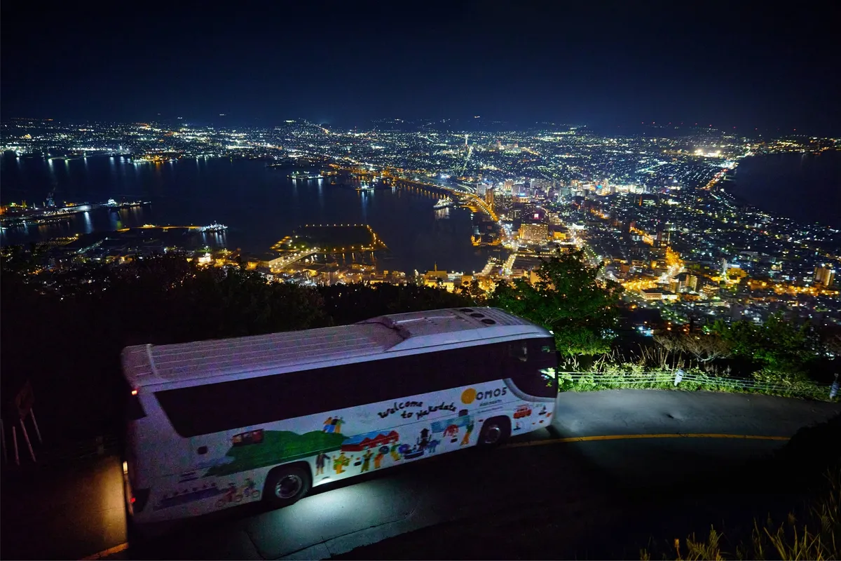 函館山の夜景を背に走る専用バス
