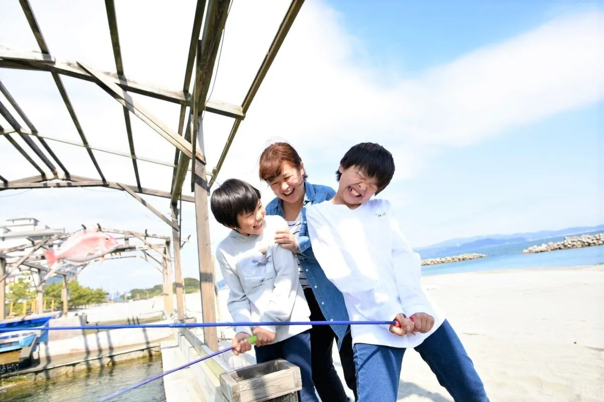 鳴門の海をバックに釣り堀体験を楽しむ親子