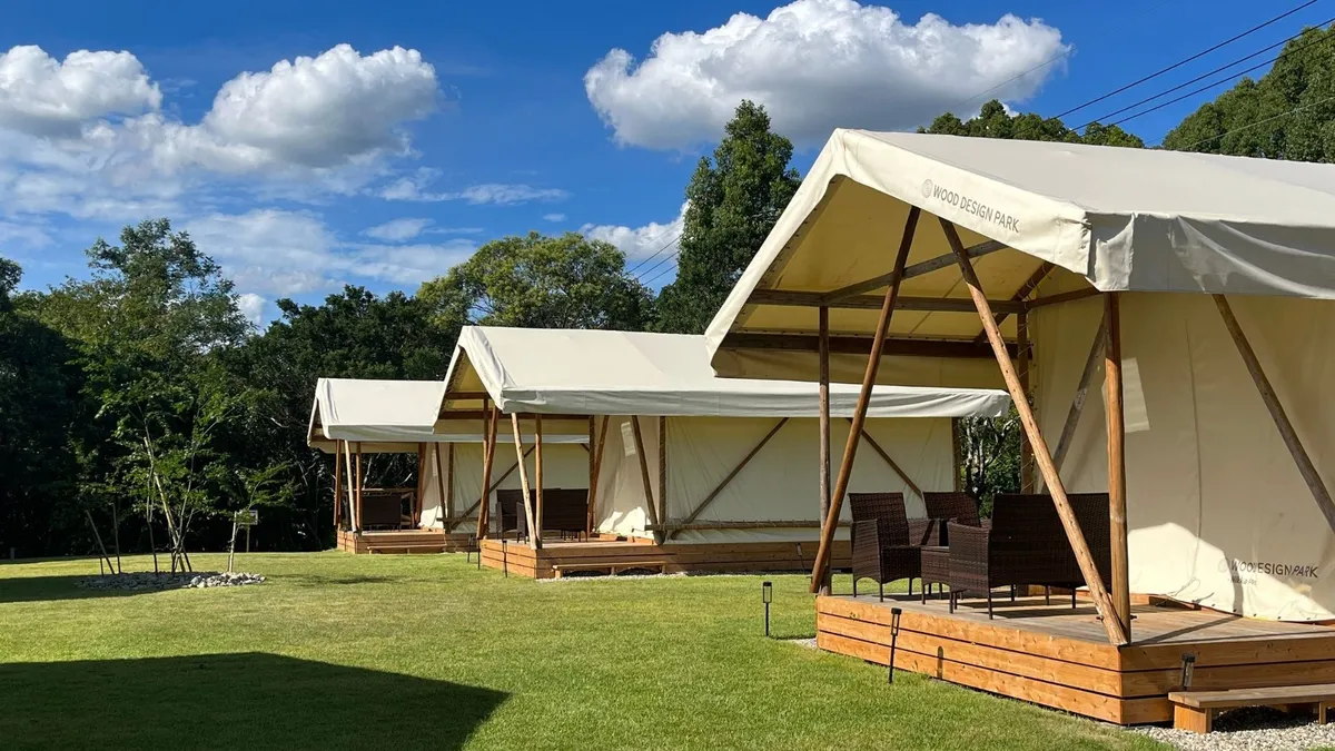 青空の下に並ぶ白いグランピングテント