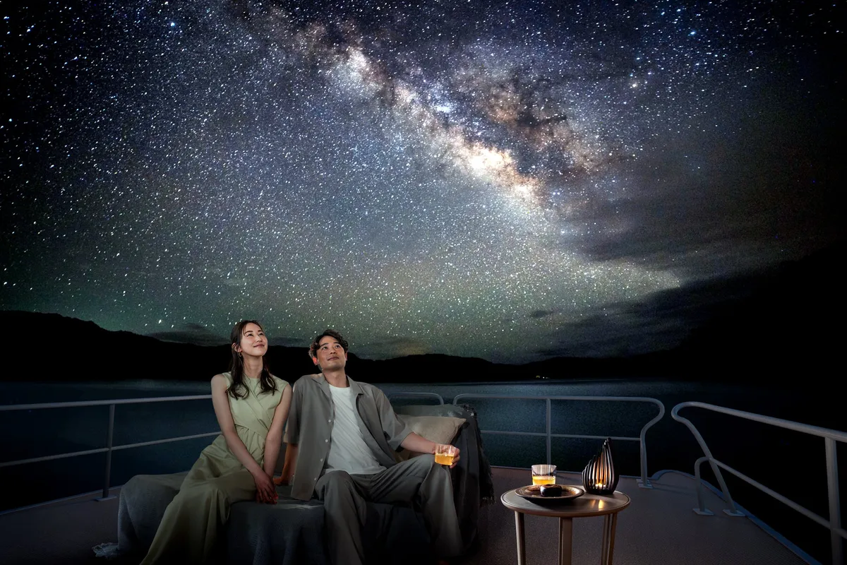 満天の星空の下、デッキで寛ぐカップル