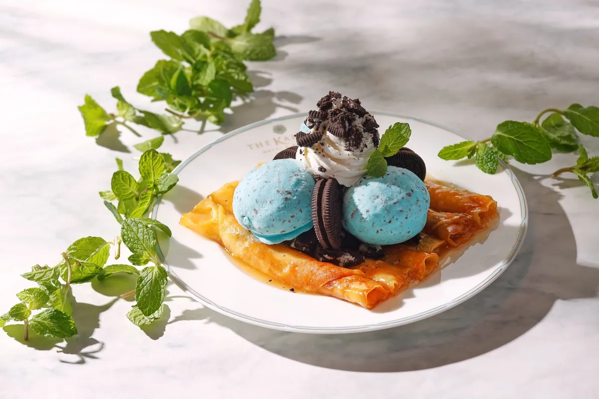 ロール状のシンパンケーキに青いチョコミントアイスとクッキーが添えられた一皿