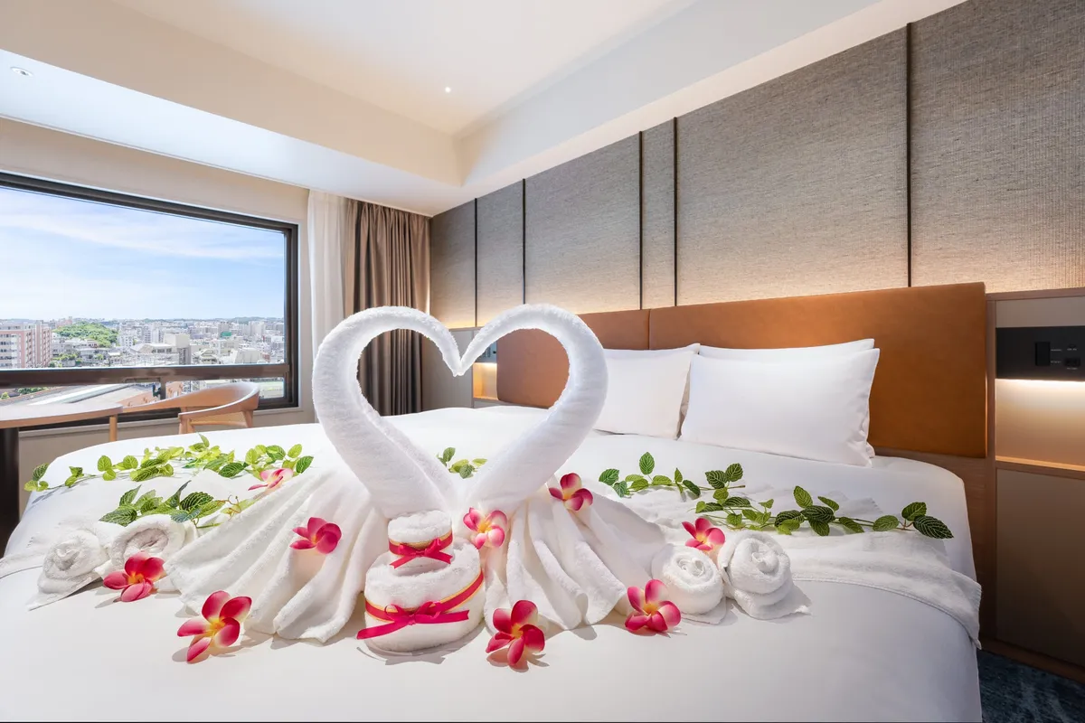 客室のベッド上に用意された、スワンのタオルアートと色鮮やかな花々のデコレーション