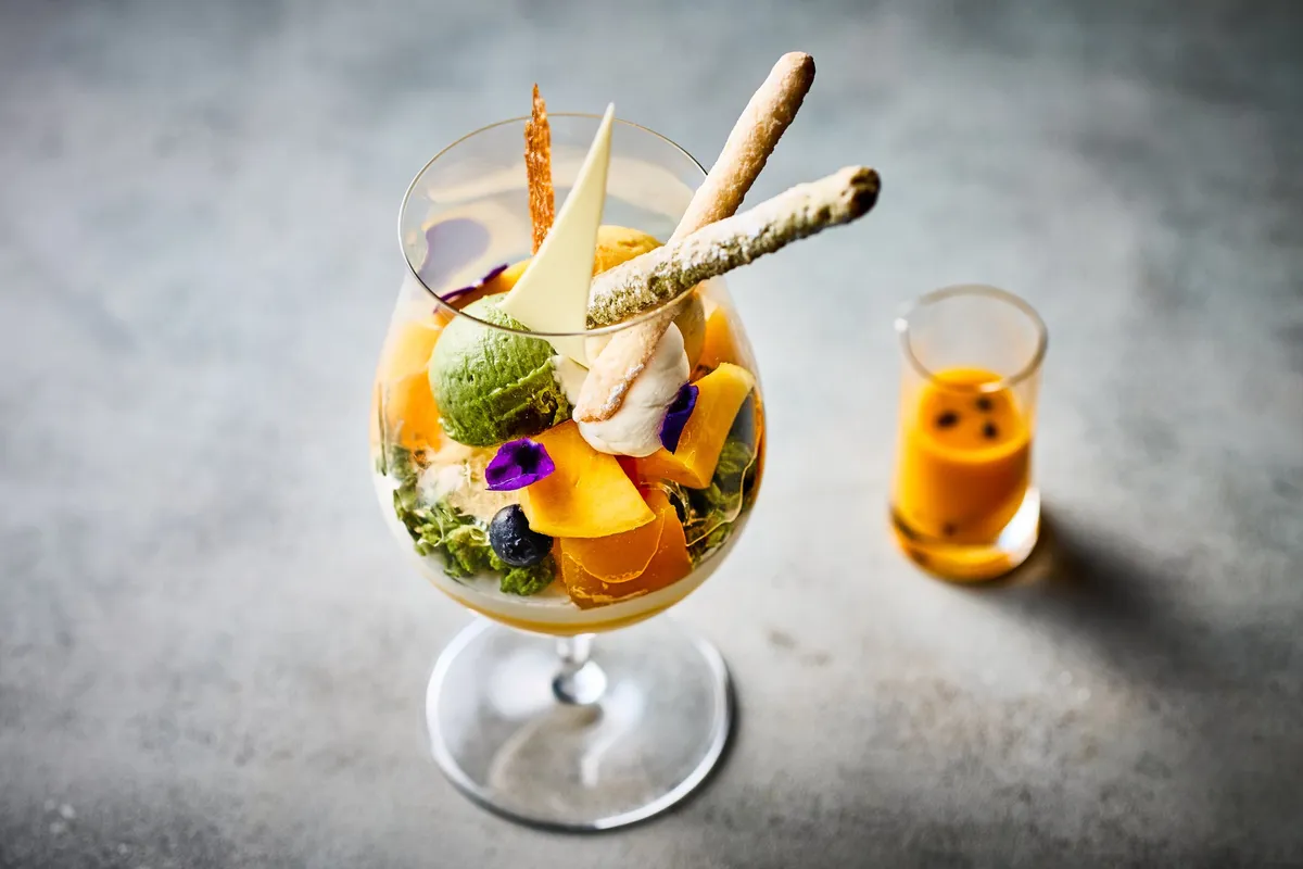 フレッシュマンゴーや抹茶アイス、エディブルフラワーが繊細に盛り付けられたパフェのアップ