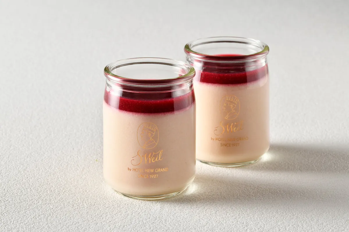 瓶に入った桃のババロア。淡いピンク色の層の上に赤いソースがかかっている。