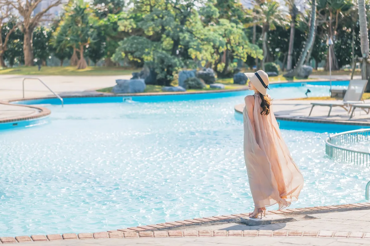 屋外プールのほとりでリゾートの風を感じる女性の様子