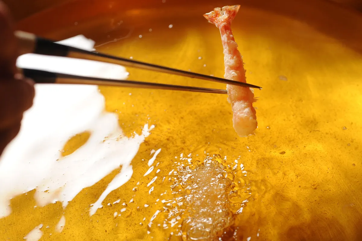 黄金色の油で鮮やかに揚げられる大ぶりの海老天ぷら