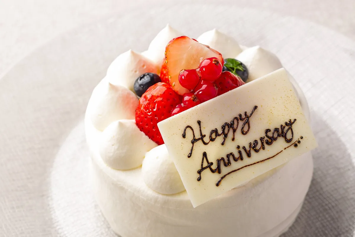 Happy Anniversaryのメッセージプレートが添えられた、苺とベリーのデコレーションケーキ