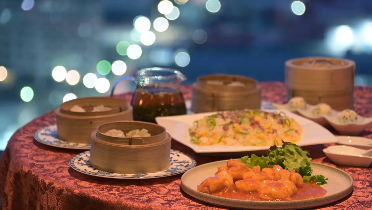 夜景をバックにテーブルに並ぶエビチリや点心などの本格中華料理