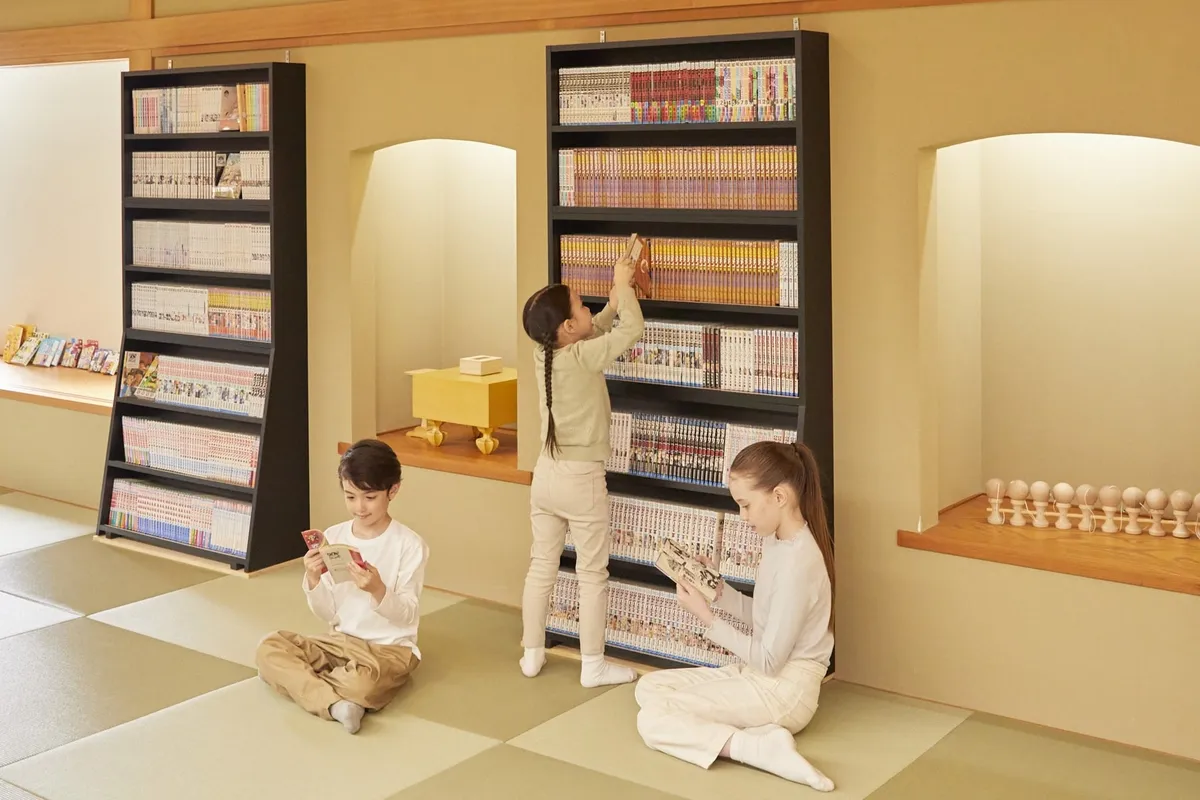 壁一面の漫画棚から本を選ぶ子供たち