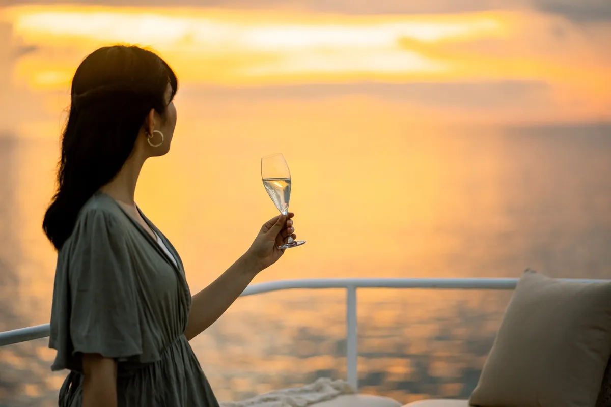 夕日を背景にシャンパングラスを持つ女性