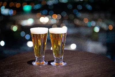 美しい夜景を背景に、テーブルに置かれた2杯の生ビールが黄金色に輝く様子