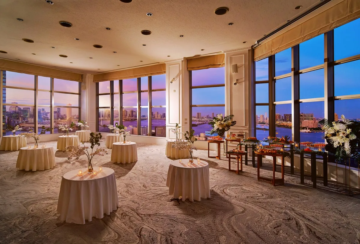大きな窓から都会の夜景を望む、立食パーティー形式の会場設営