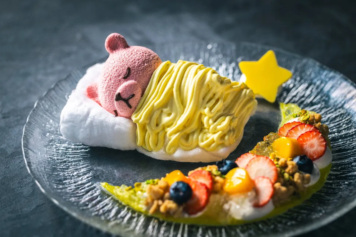 黄色い布団を被って眠るピンクのクマのムースケーキ