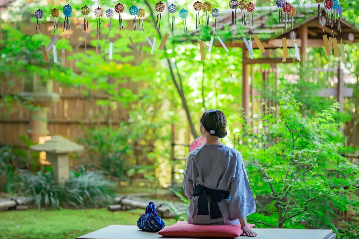 風鈴が揺れる庭園で涼む浴衣姿の女性