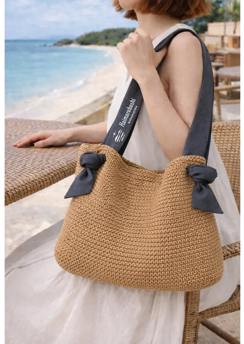 海辺のテラス席で女性が肩にかけている、リボンがアクセントになったオリジナルのジュートバッグ
