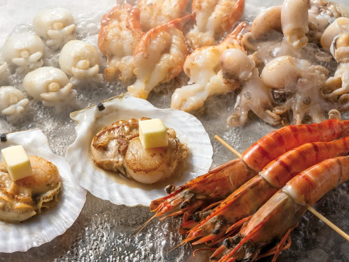 鉄板で焼き上げられる帆立や海老などの海鮮焼き