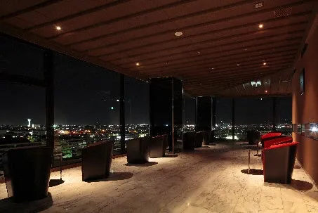 落ち着いた照明の中に函館の夜景が浮かび上がる、夜のラグジュアリーなラウンジ