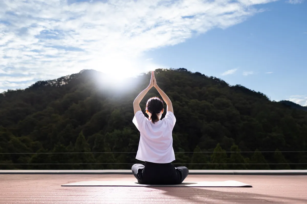屋上のウッドデッキで山々を背景に行う天空ヨガ