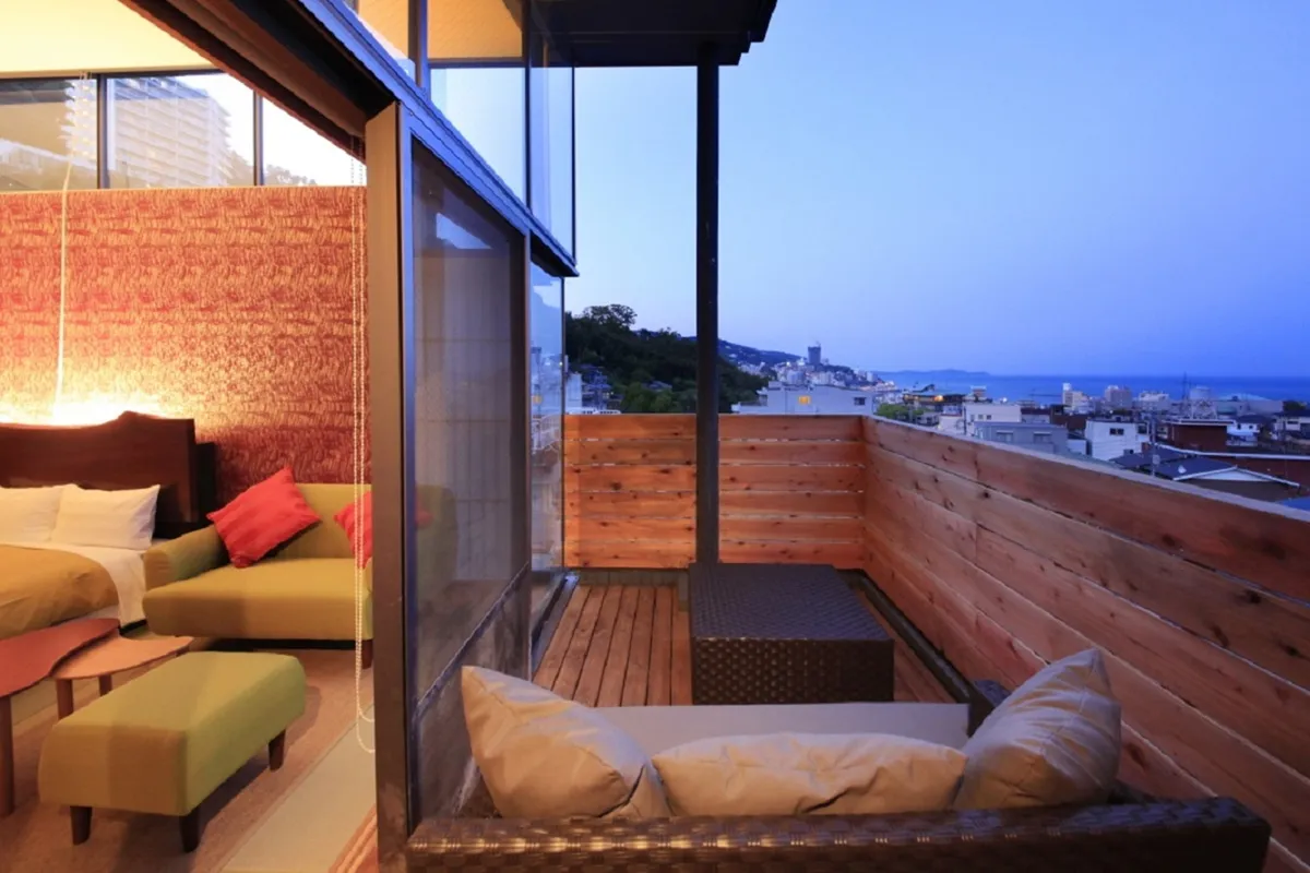 夕暮れ時の熱海の街並みと海を一望する客室テラス