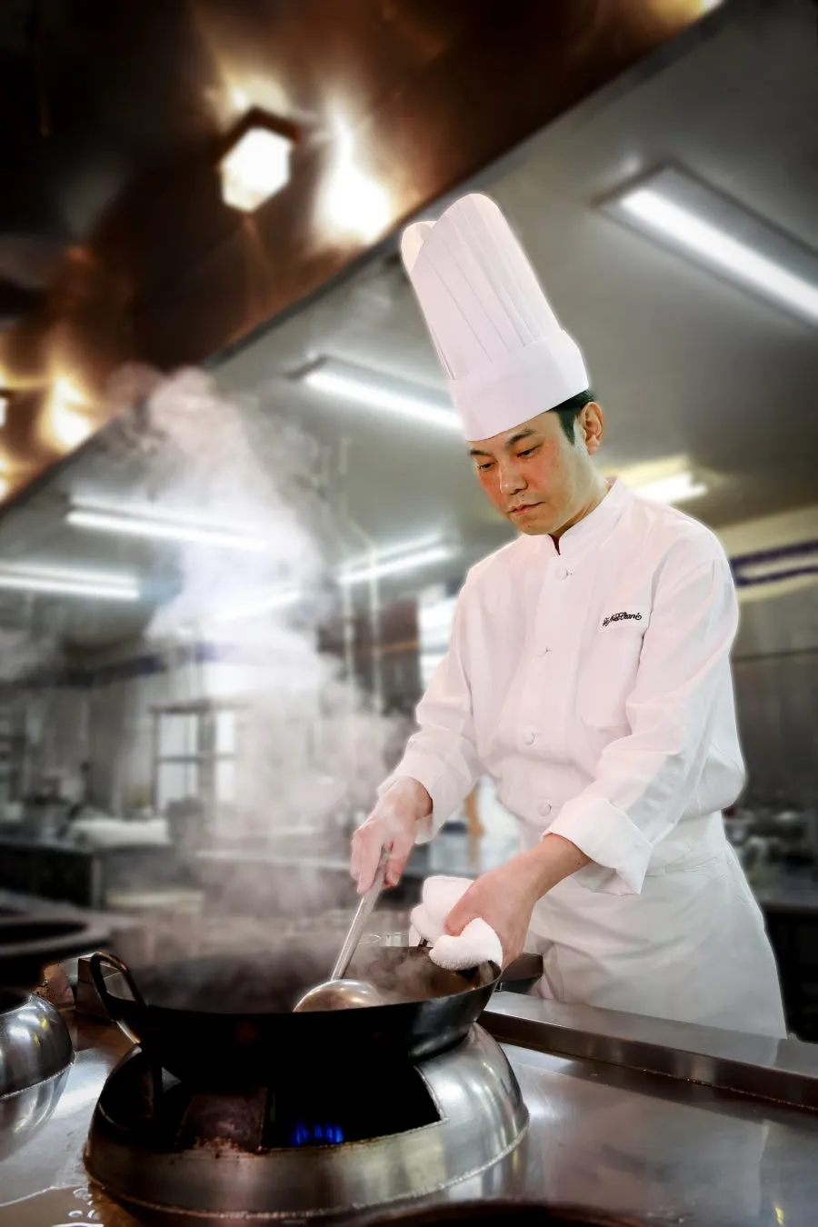 真剣な眼差しで中華鍋を振る今井健料理長