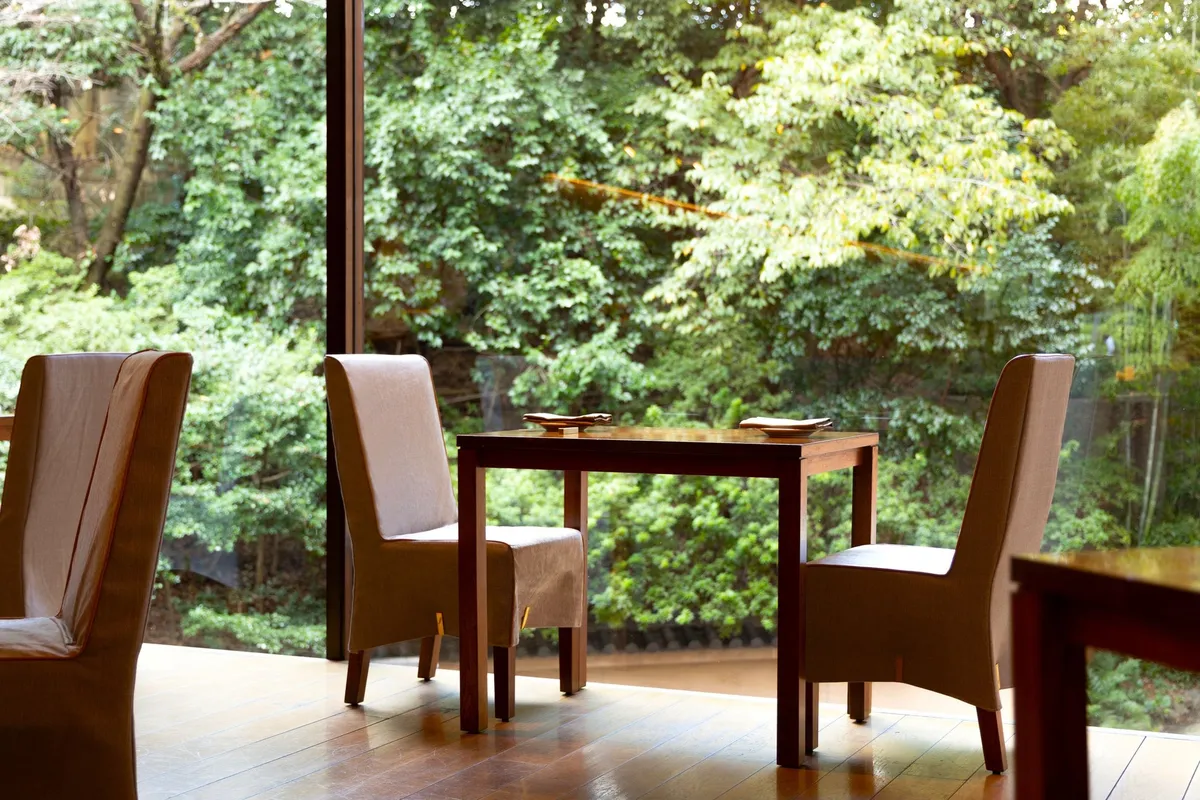 新緑の庭園を望む落ち着いた雰囲気のレストラン内観