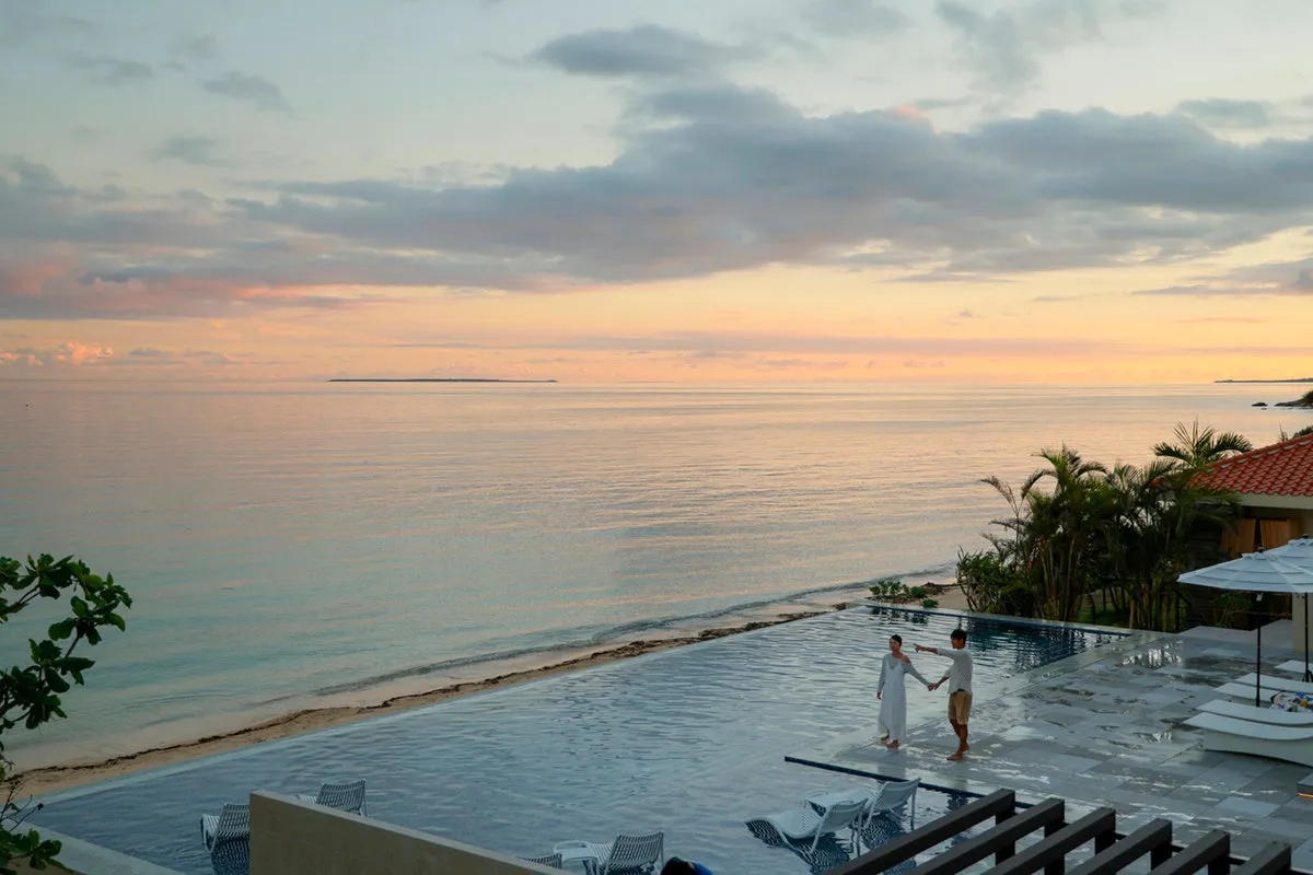夕暮れ時の空が水面に映り込む、幻想的な雰囲気のインフィニティプールと寄り添うカップル