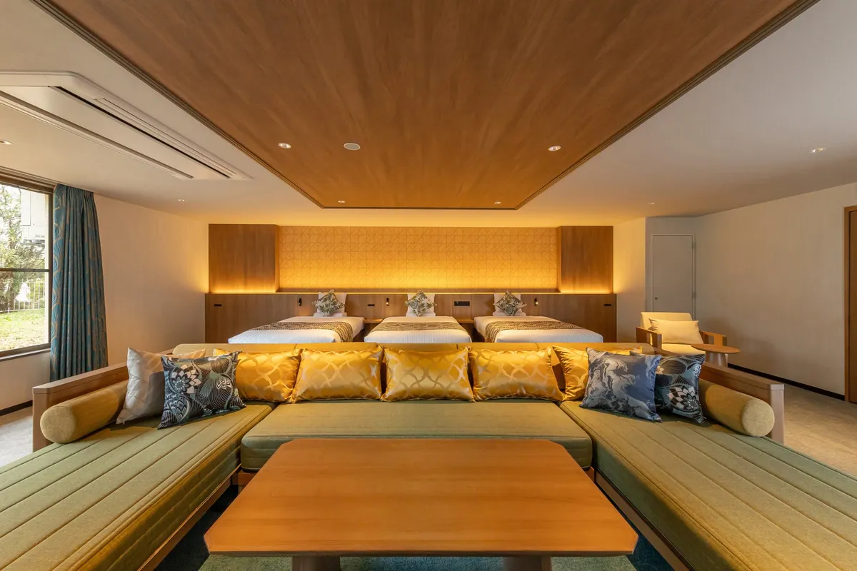 大きなソファと複数のベッドを備えたモダンで広々とした新客室