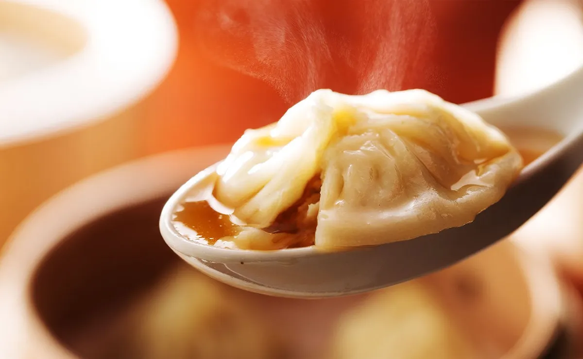 レンゲに乗せられた熱々で肉汁たっぷりの小籠包