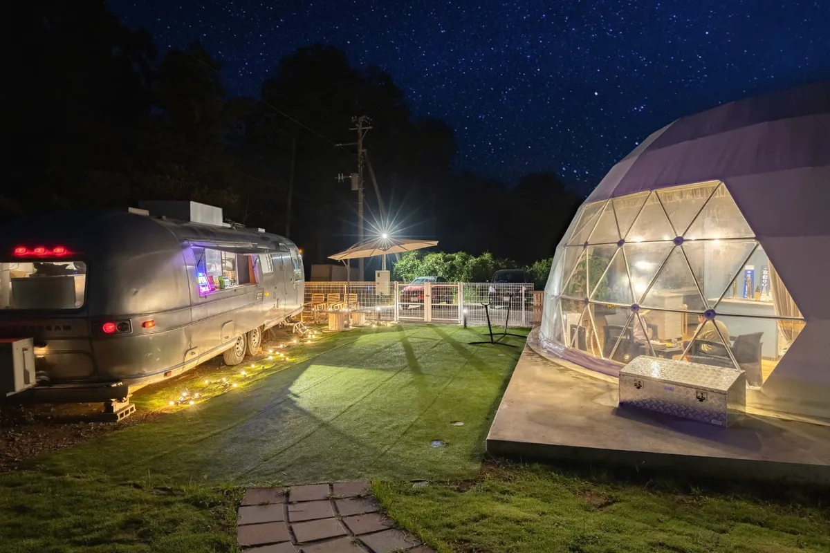 星空の下でライトアップされた夜のドームテントとトレーラー