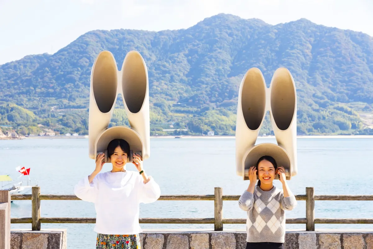 うさぎの耳を模した大きな集音器を頭に当てて笑顔を見せる女性二人