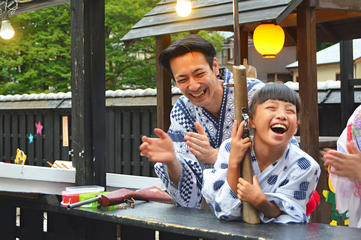 縁日で射的に挑戦する親子