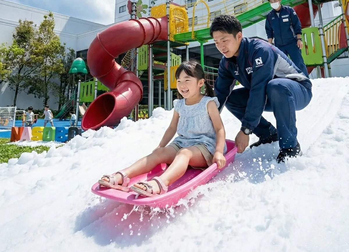 雪の斜面をソリで滑る子どもとスタッフ
