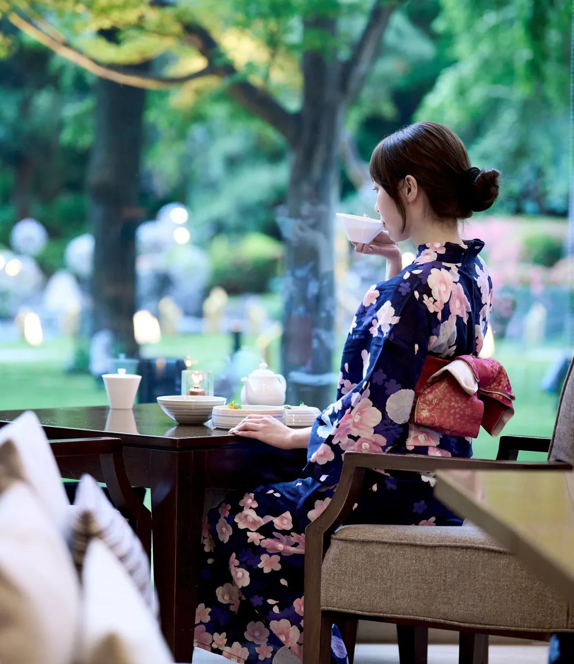 浴衣姿で庭園を眺めながらティータイムを過ごす女性