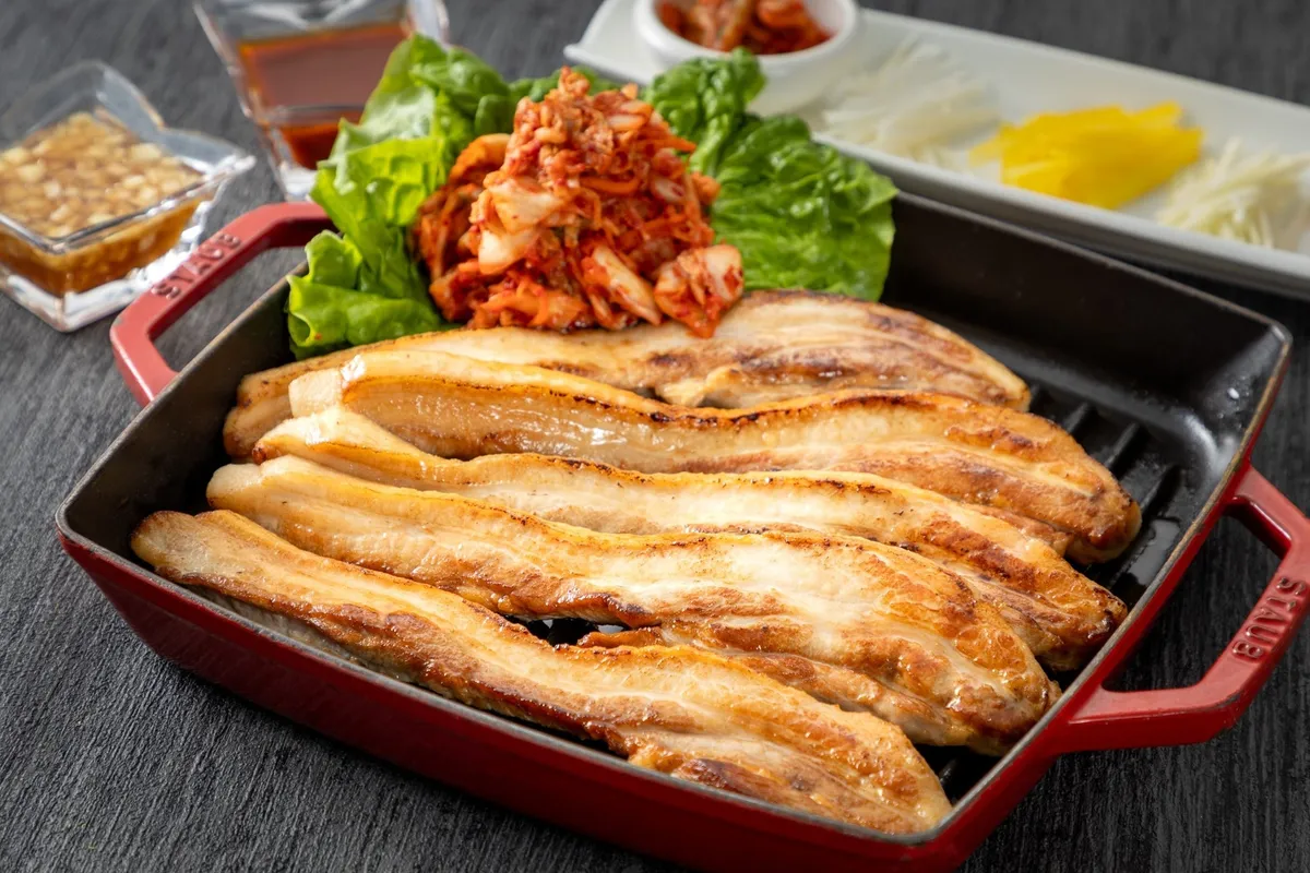 STAUBの鍋で提供される厚切り肉のサムギョプサルとキムチ