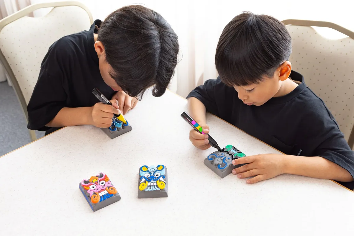 真剣に鬼瓦へ色を塗る子供たち