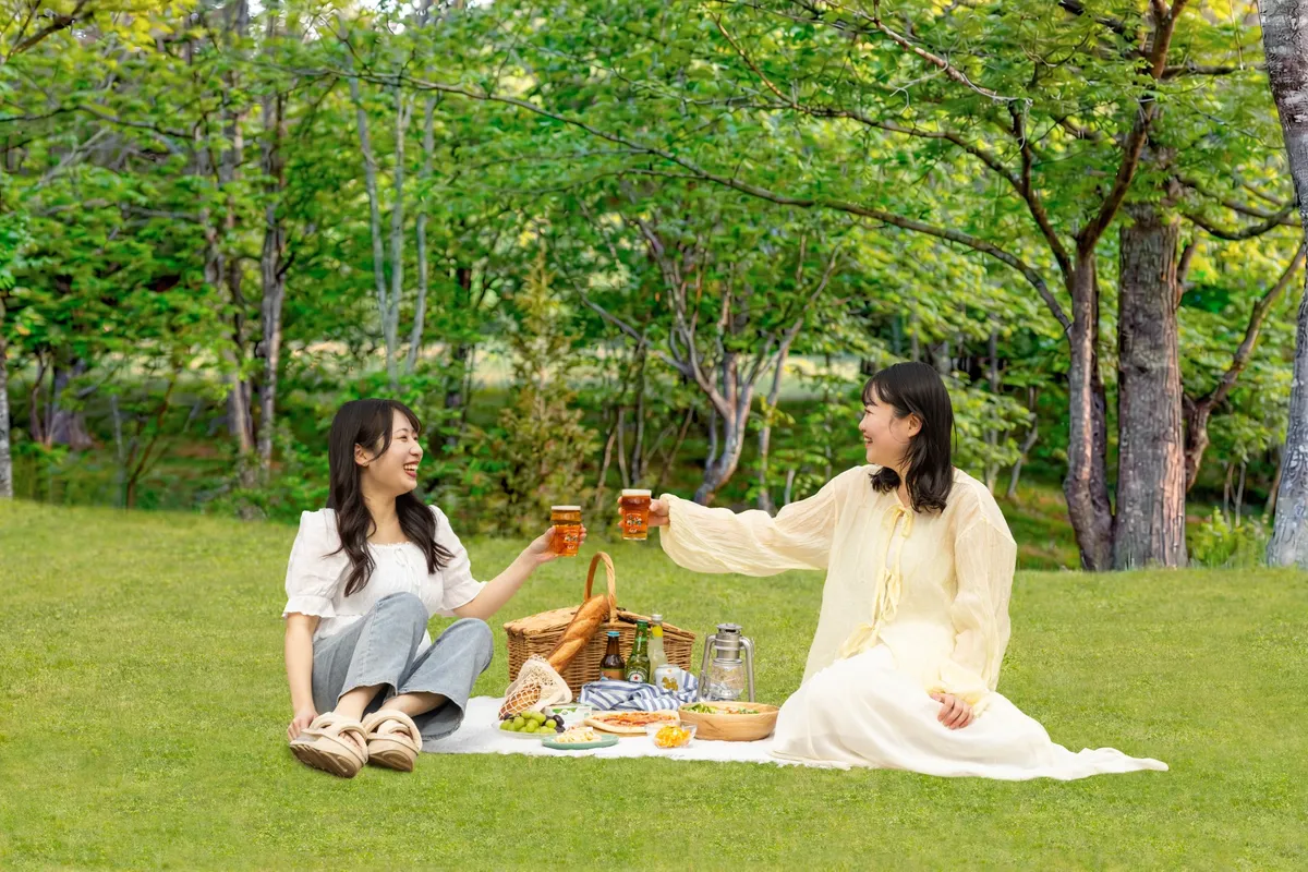 芝生の上でピクニックセットを広げて乾杯する女性たち
