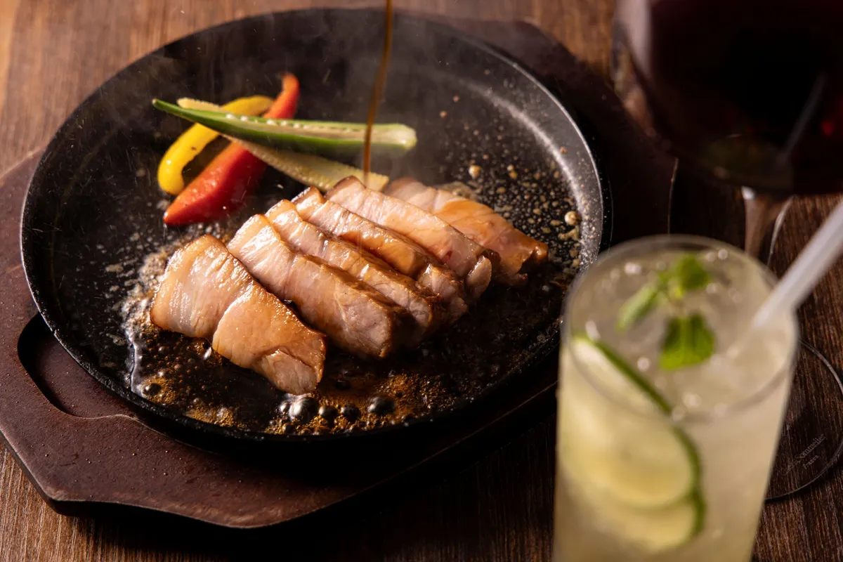 熱々の鉄板でジューシーに焼き上げられた豚肉料理のアップ