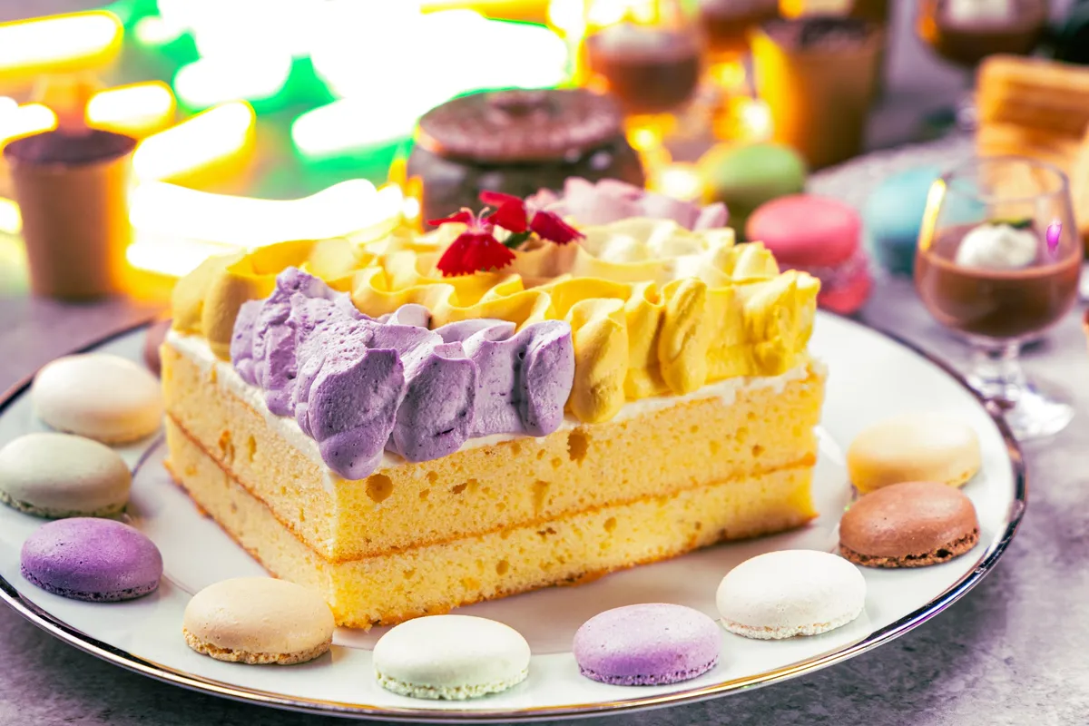 カラフルなクリームでデコレーションされたレインボーケーキとマカロン