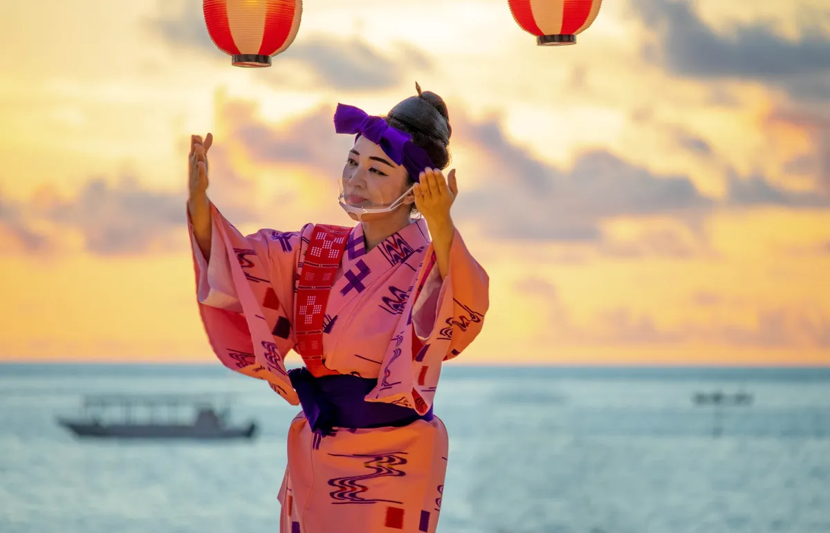 夕暮れの海を背景に踊る沖縄の伝統舞踊
