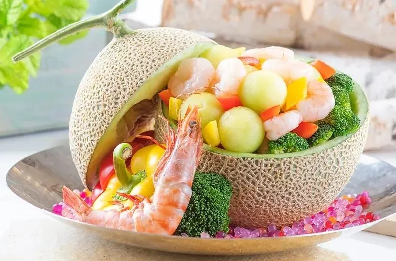 メロンの器に海老や野菜がたっぷり入った華やかな塩炒め