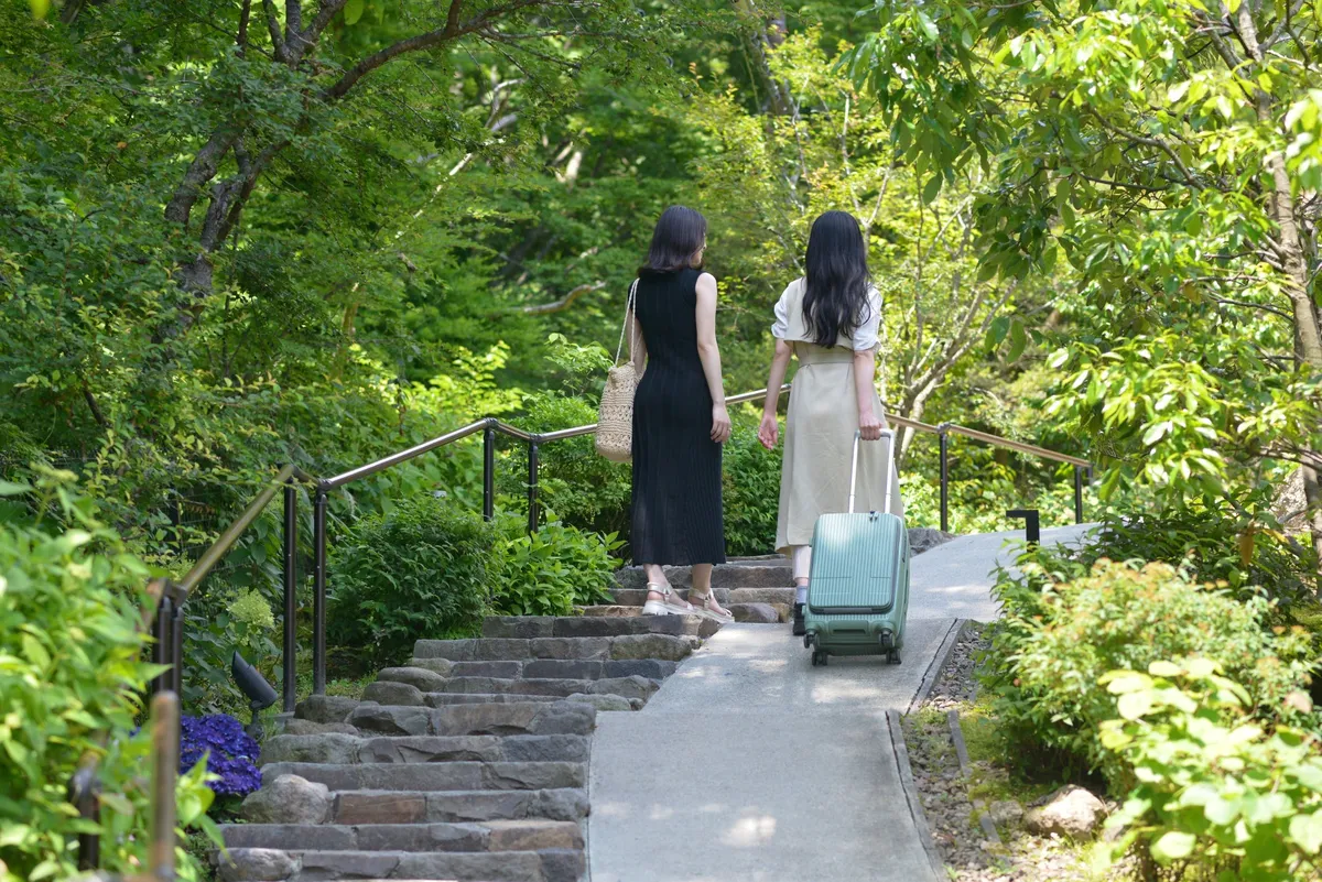 緑豊かなアプローチを歩く女性二人