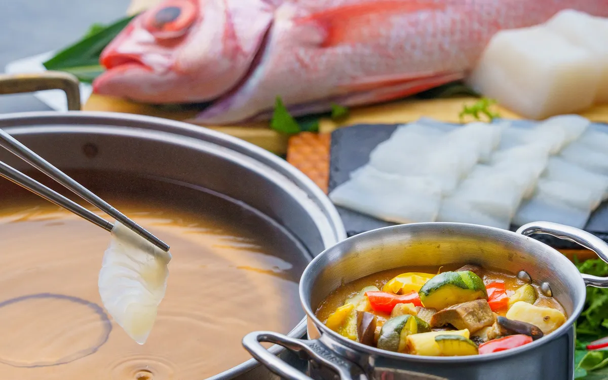 トムヤムクンのスープに白身魚をくぐらせる様子
