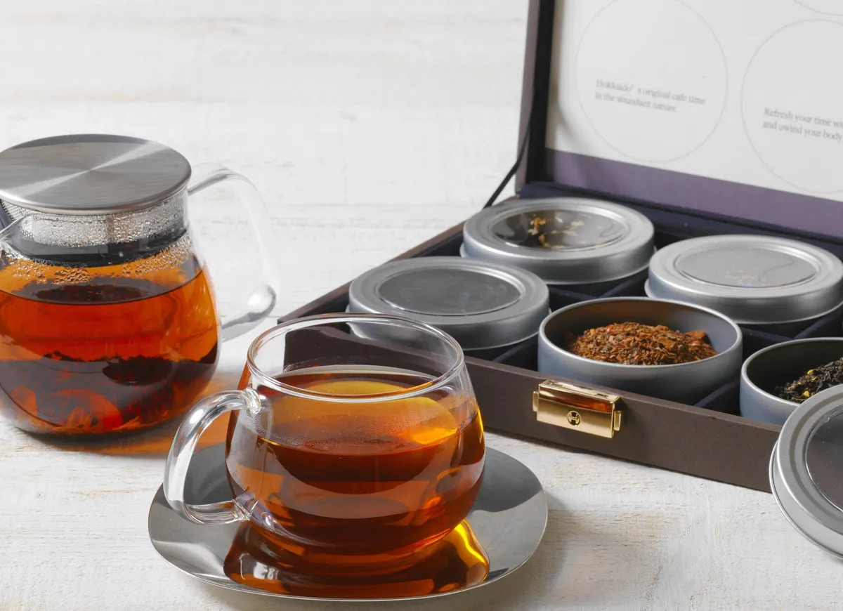 ポットとカップに入れられた紅茶と数種類の茶葉が入ったボックス