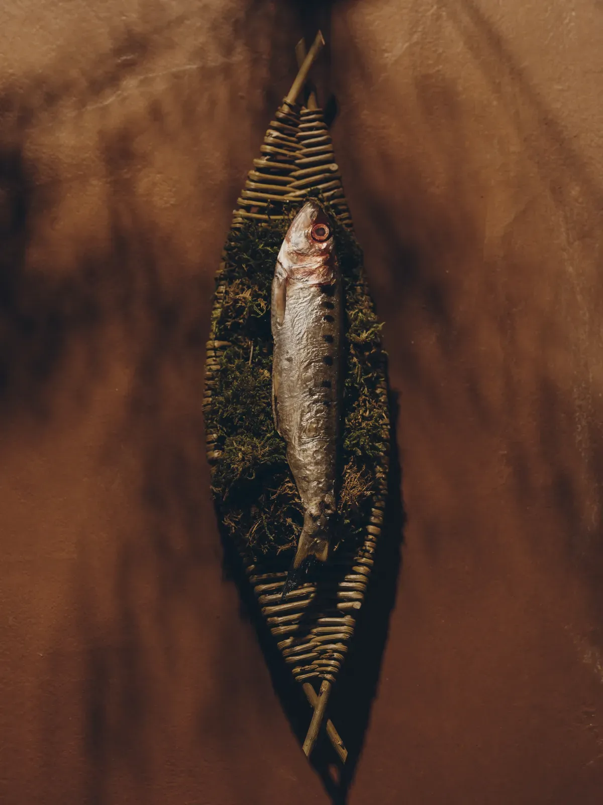 苔の敷かれた籠の上に美しく盛り付けられた、一匹の川魚の料理