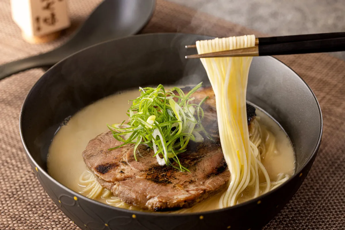 箸で持ち上げられた美しい細麺と濃厚なスープ