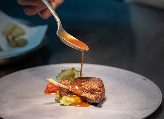 フランス料理のメインディッシュにソースをかける様子