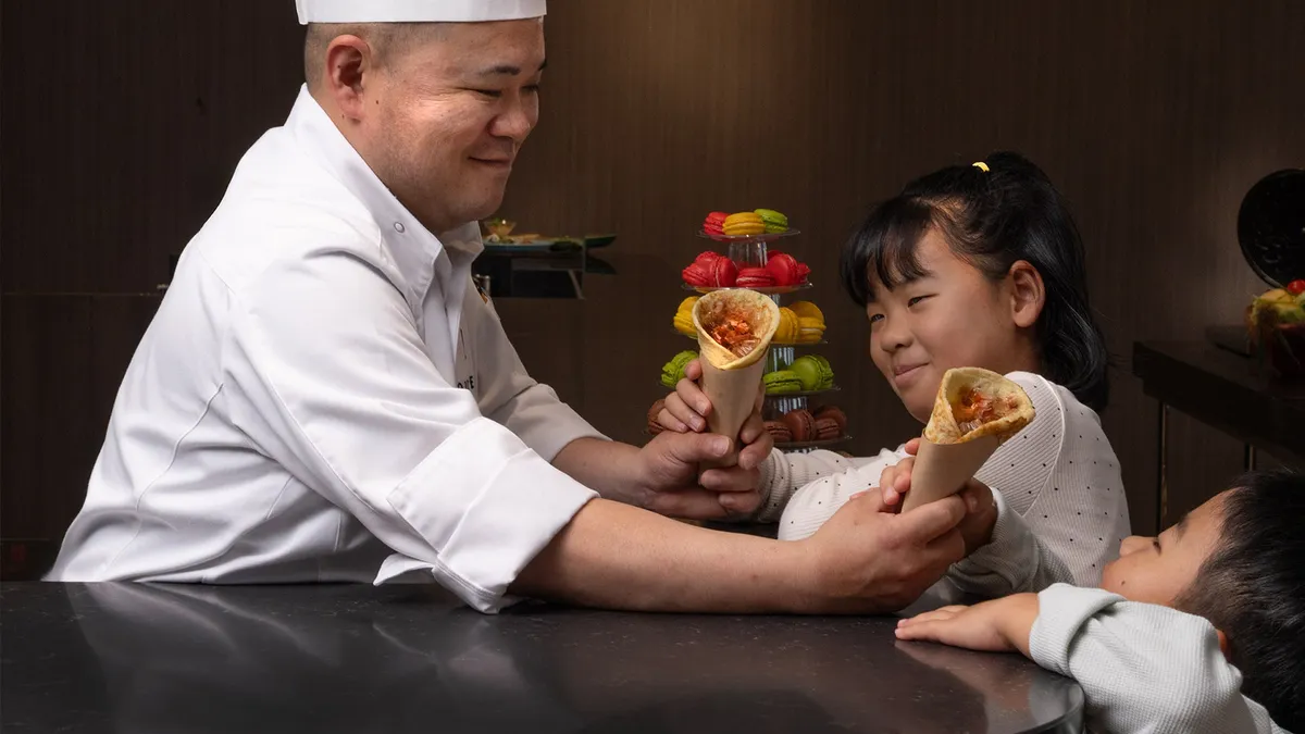 シェフから手渡しされる焼きたてメニュー