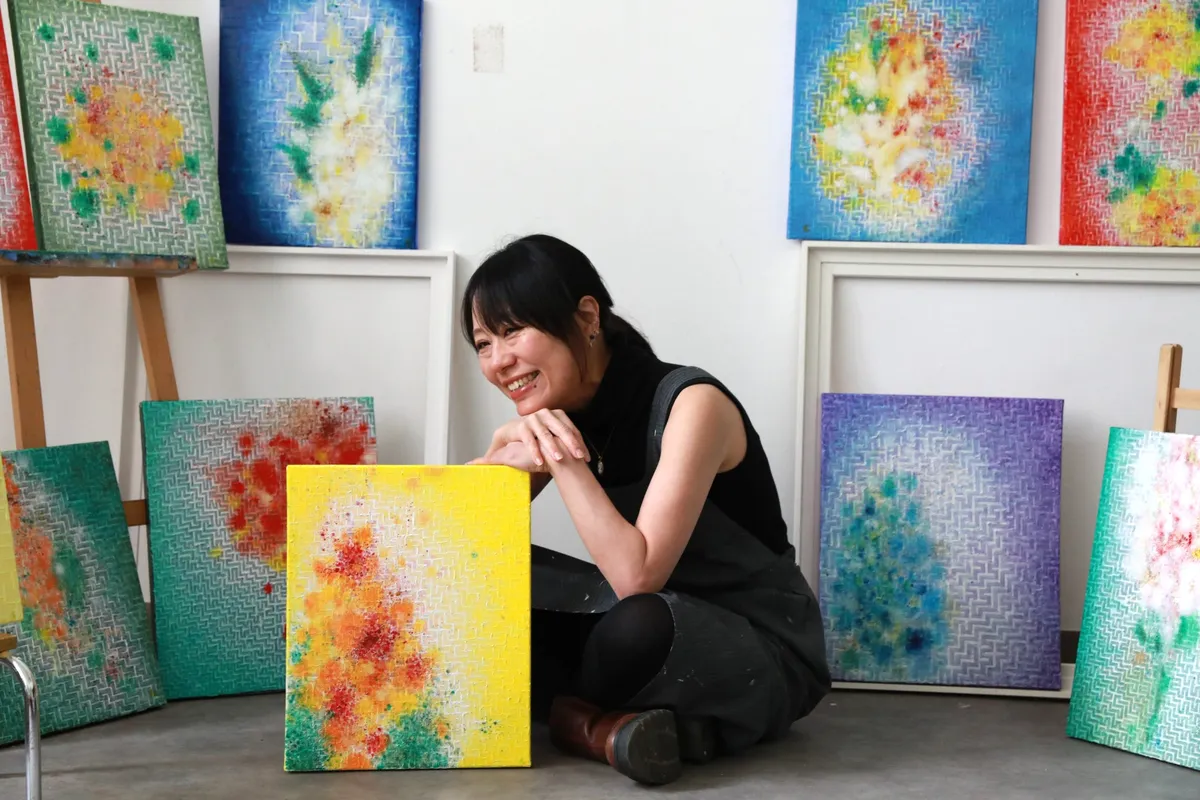 色鮮やかな新作絵画に囲まれて微笑むみうらあんこ氏